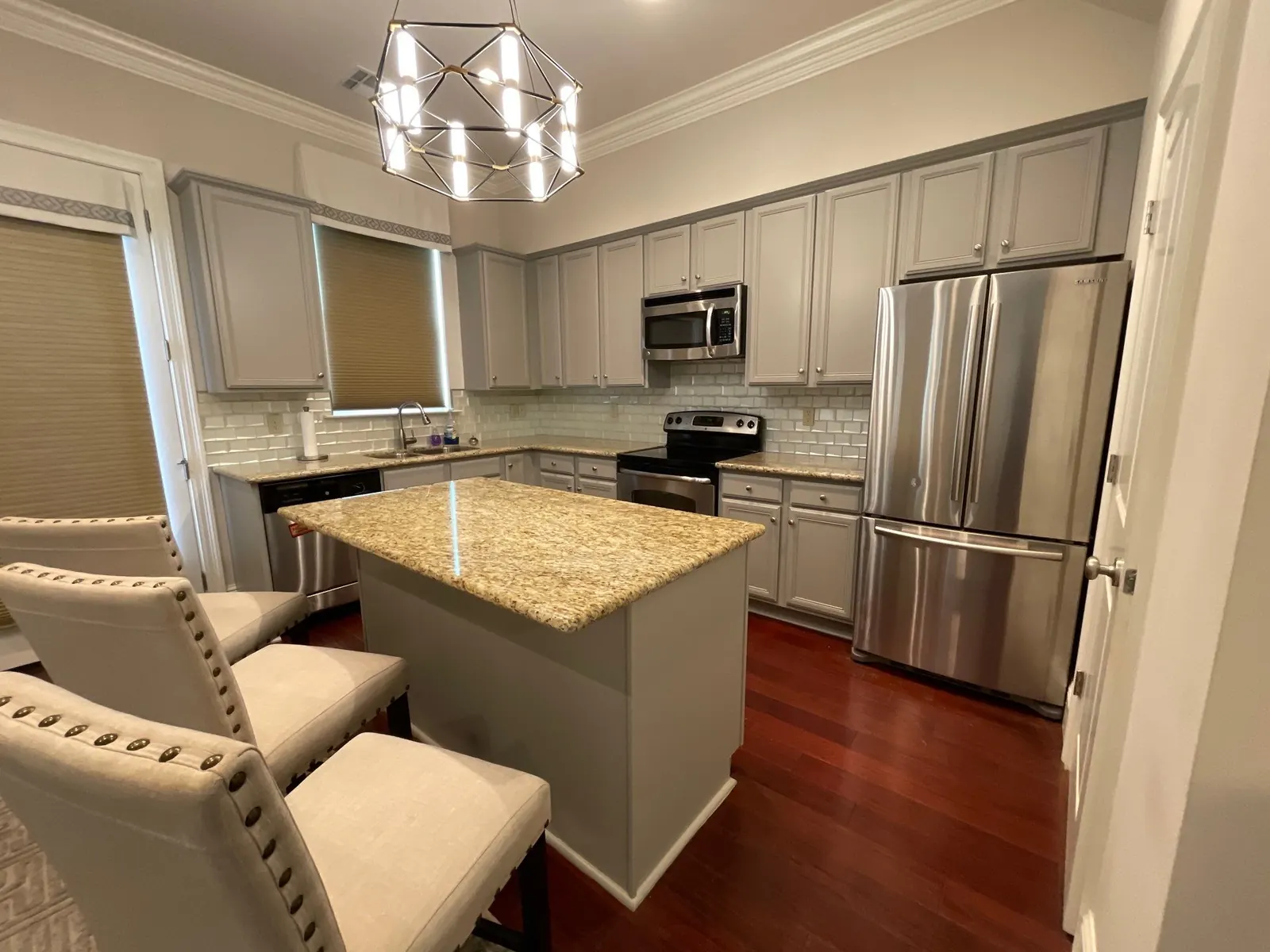 Repainted gray kitchen cabinets with a granite island and stainless appliances