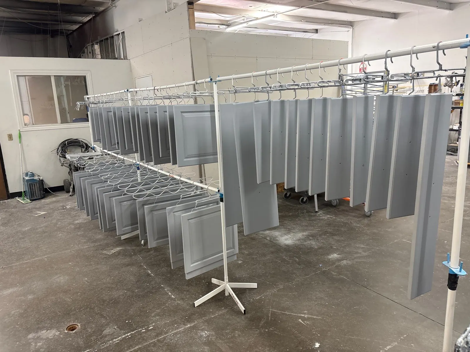 Rows of cabinet doors hung on racks to cure in the Kind Home paint shop